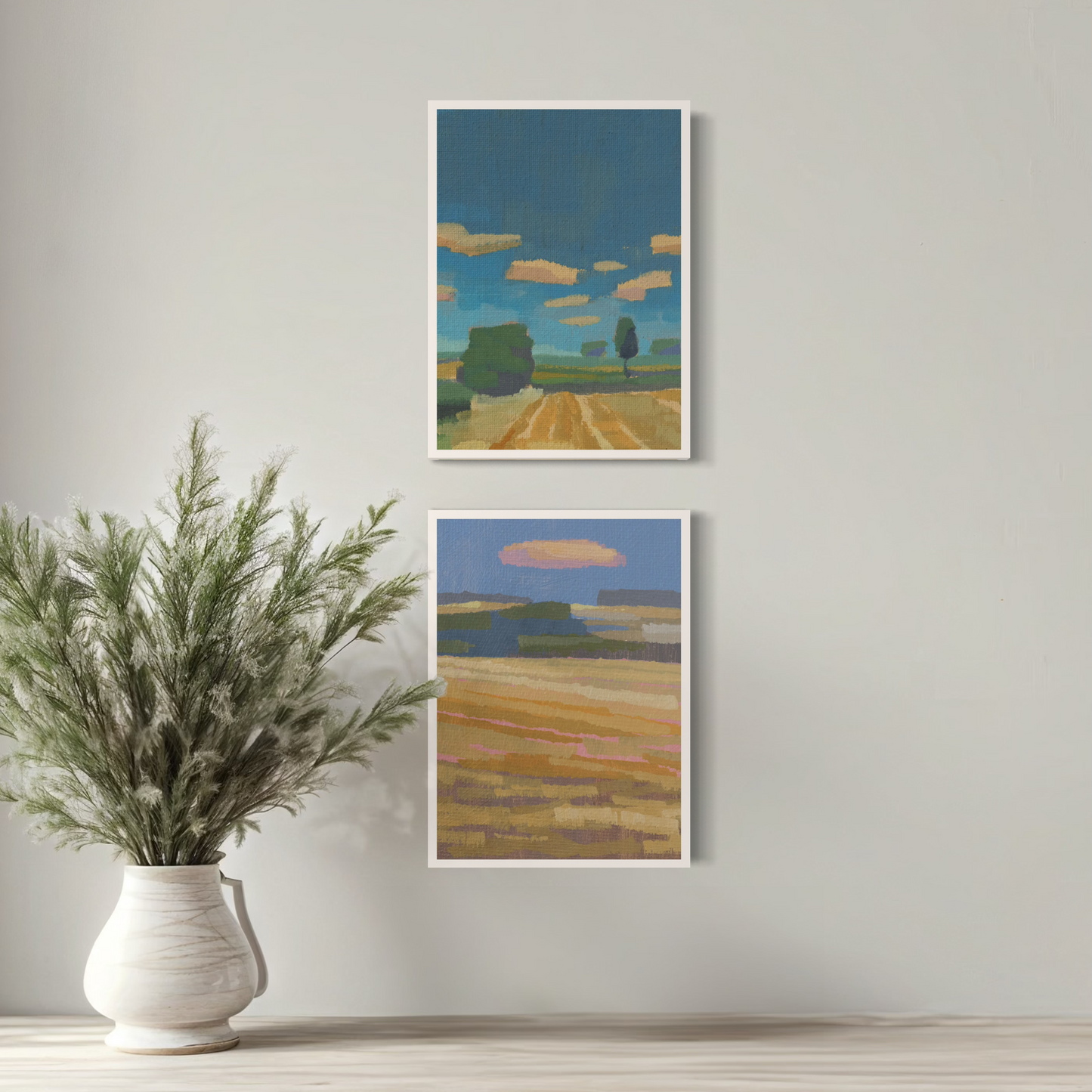 Zwei Mini-Poster mit Landschaftsmotiven und heiterem Wolkenhimmel über einer Pflanze in einem weißen Gefäß.